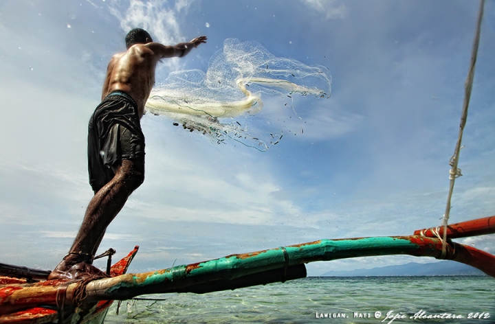 Fisherman casts his net by Jojie Alcantara